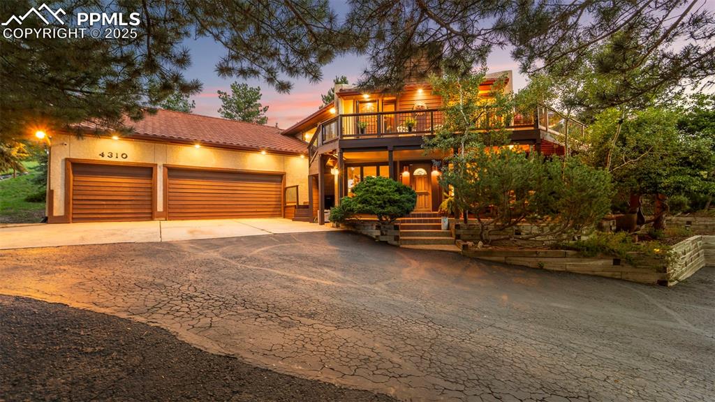 Caption: At twilight, this front facade of a retreat-style home glows warmly, its architectural lines softene