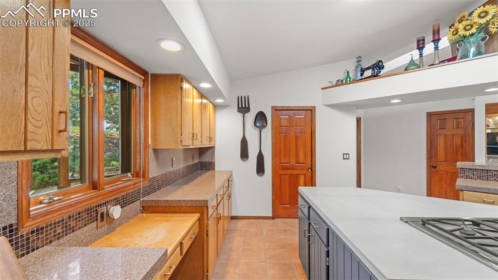 Image 13 of 46: Kitchen with backsplash, recessed lighting, light tile patterned floors, an