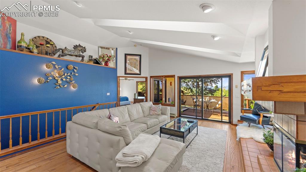 Image 18 of 46: Living area with wood finished floors, lofted ceiling, and a glass covered 