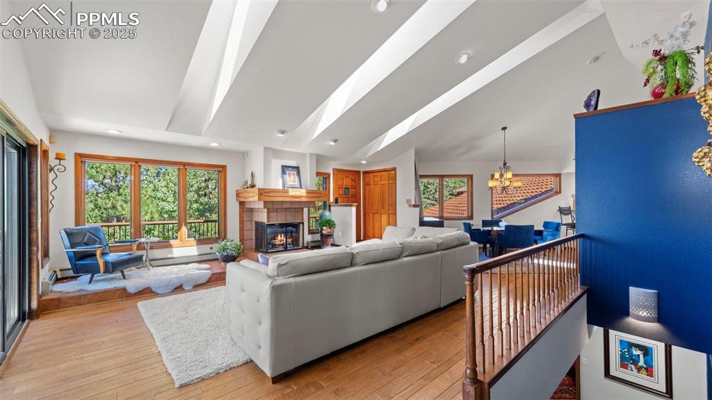 Image 19 of 46: Living room featuring a tiled fireplace, wood-type flooring, a chandelier, 