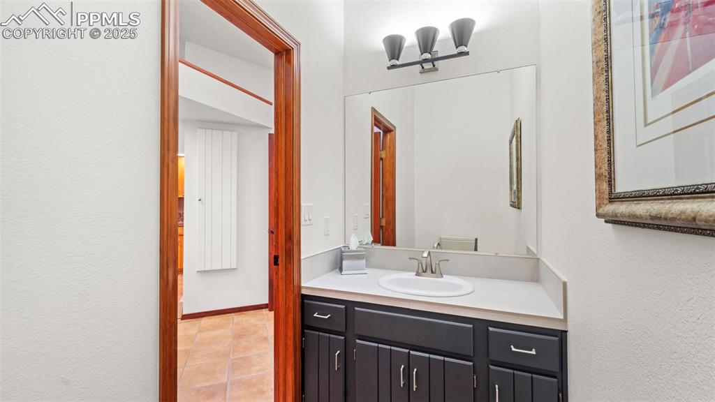 Image 21 of 46: Half bath featuring vanity, light tile patterned flooring, and a textured w