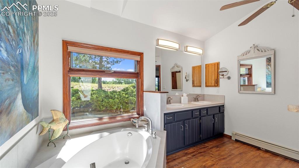 Image 29 of 46: Bathroom featuring a baseboard heating unit, double vanity, a bath, dark wo