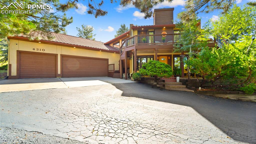 Image 3 of 46: View of front of property with a garage, driveway, stucco siding, a chimney