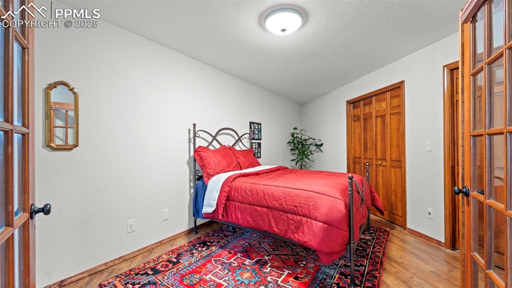 Image 32 of 46: Bedroom with wood finished floors, a closet, and french doors