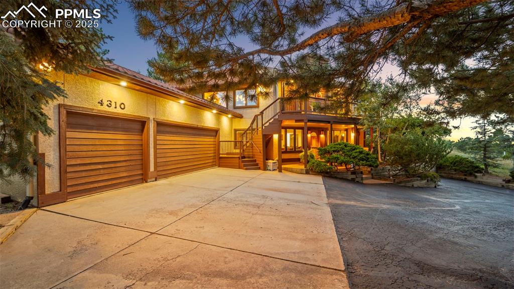 Image 44 of 46: View of front of home with stairs, stucco siding, driveway, and a deck