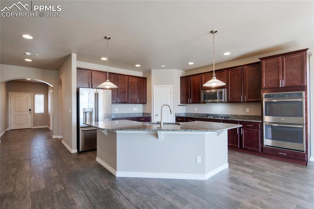 Image 11 of 36: The kitchen features dark wood cabinetry, stainless steel appliances, and a