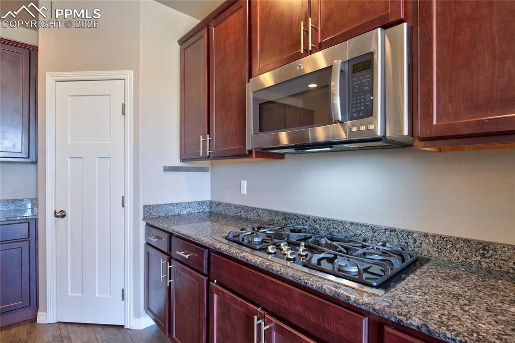 Image 12 of 36: The kitchen features rich wood cabinetry, speckled granite countertops, a s