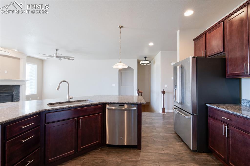 Image 13 of 36: The kitchen features dark wood cabinetry, granite countertops, and stainles