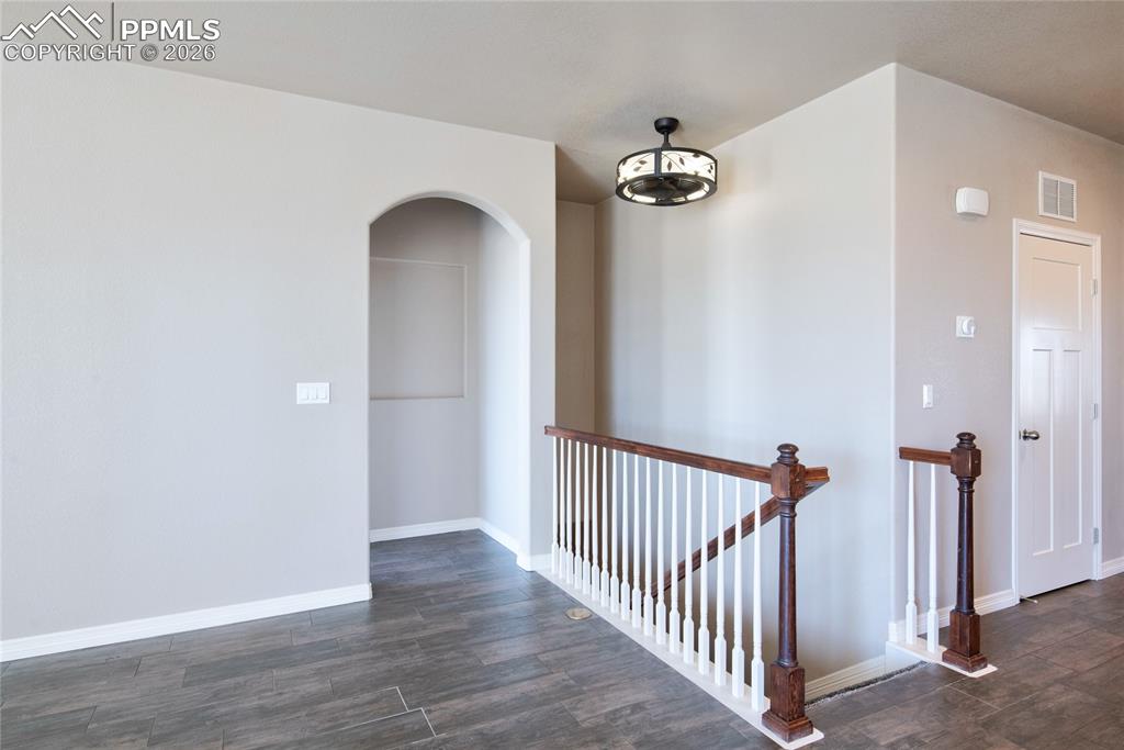 Image 14 of 36: The property features an archway, staircase with wood banisters, and plank-