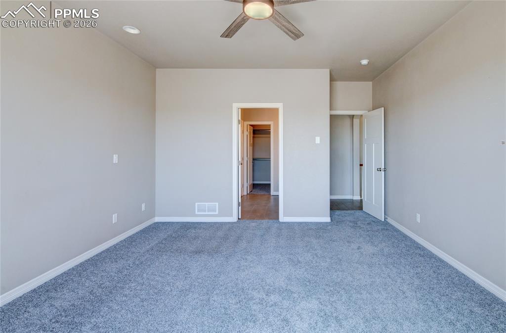 Image 16 of 36: This spacious room features neutral wall tones, blue carpeting, and a ceili