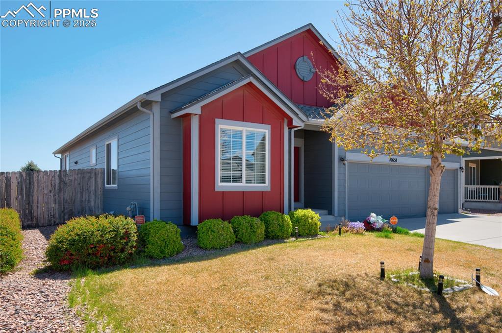 Image 2 of 36: The property features a two-car garage, a red and gray exterior, and a well