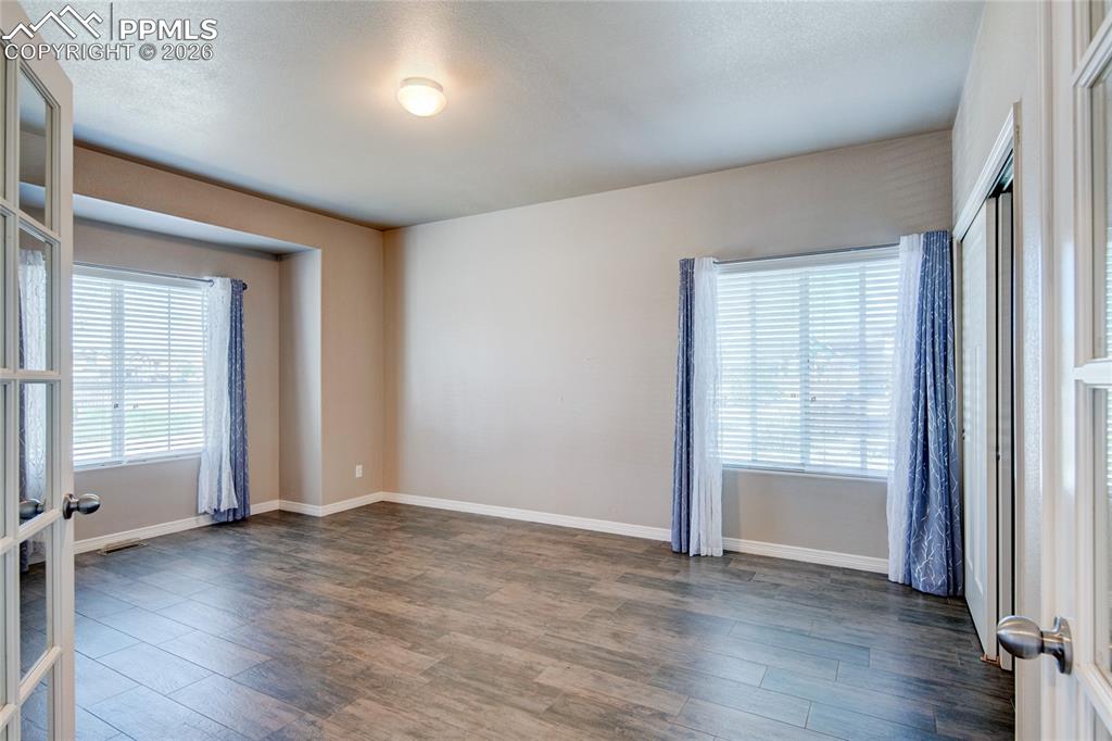 Image 20 of 36: This room features wood-look flooring, light-colored walls, and two large w