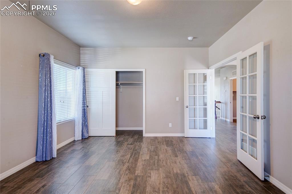 Image 21 of 36: This room features wood-look flooring, light-colored walls, a window with b