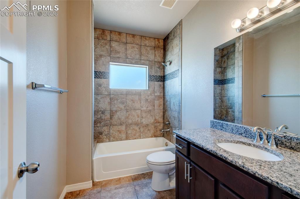 Image 22 of 36: The bathroom features a vanity with a granite countertop, a full-width mirr