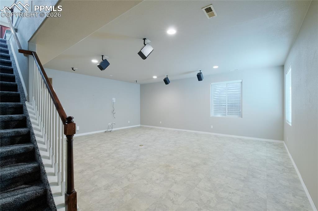 Image 24 of 36: Spacious room featuring light-colored flooring, windows with blinds, and re