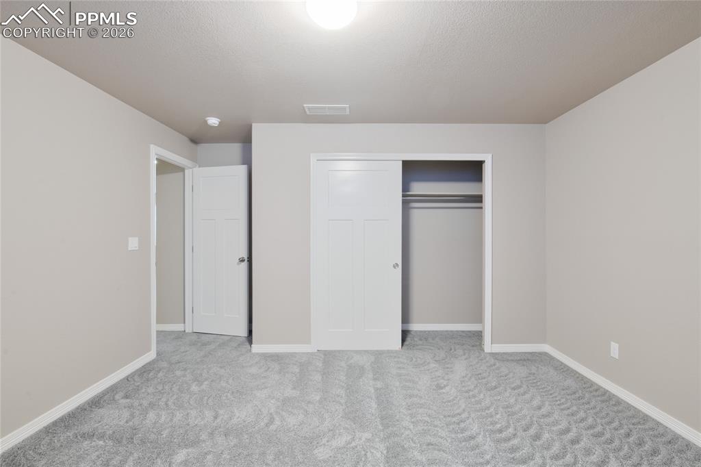 Image 29 of 36: This room features light grey walls, grey patterned carpeting, white basebo