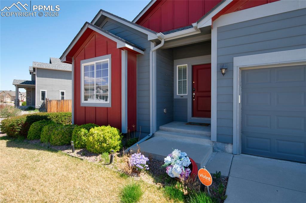 Image 3 of 36: The property features a red front door, a garage, and a concrete driveway