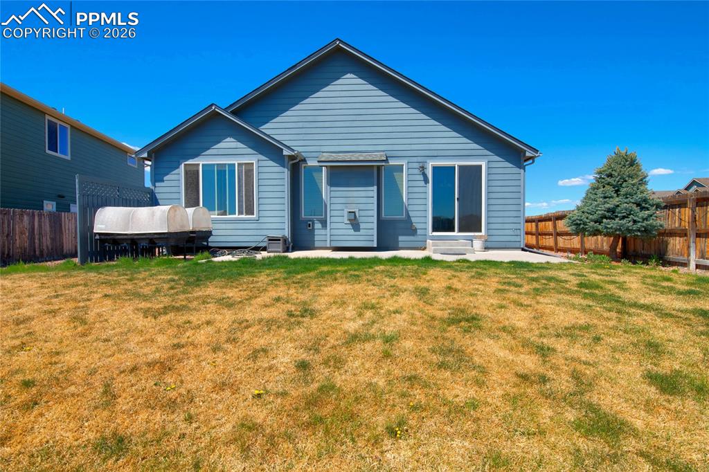 Image 32 of 36: The property features a private yard with a wooden fence and a small tree