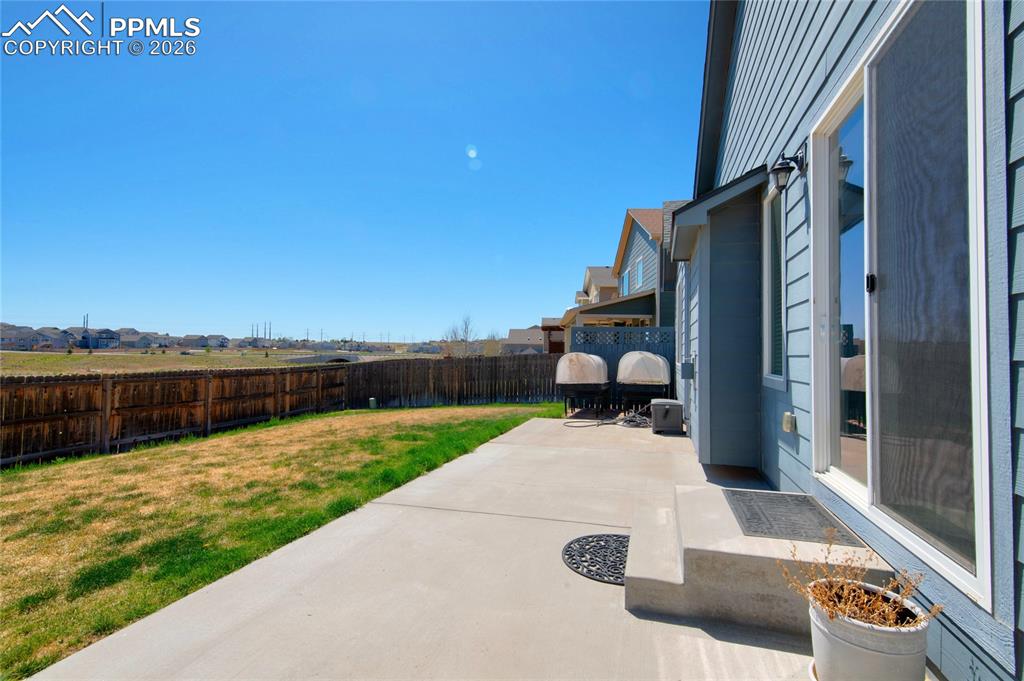 Image 33 of 36: The property features a concrete patio and a private yard with a wooden fen