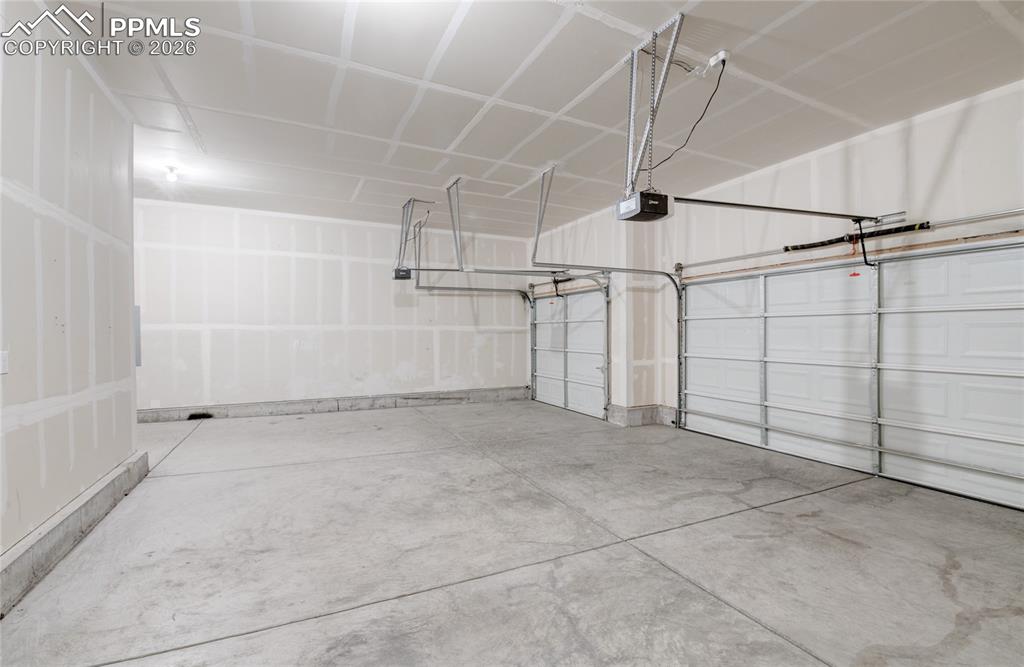 Image 36 of 36: Spacious garage featuring concrete flooring and three garage doors, providi
