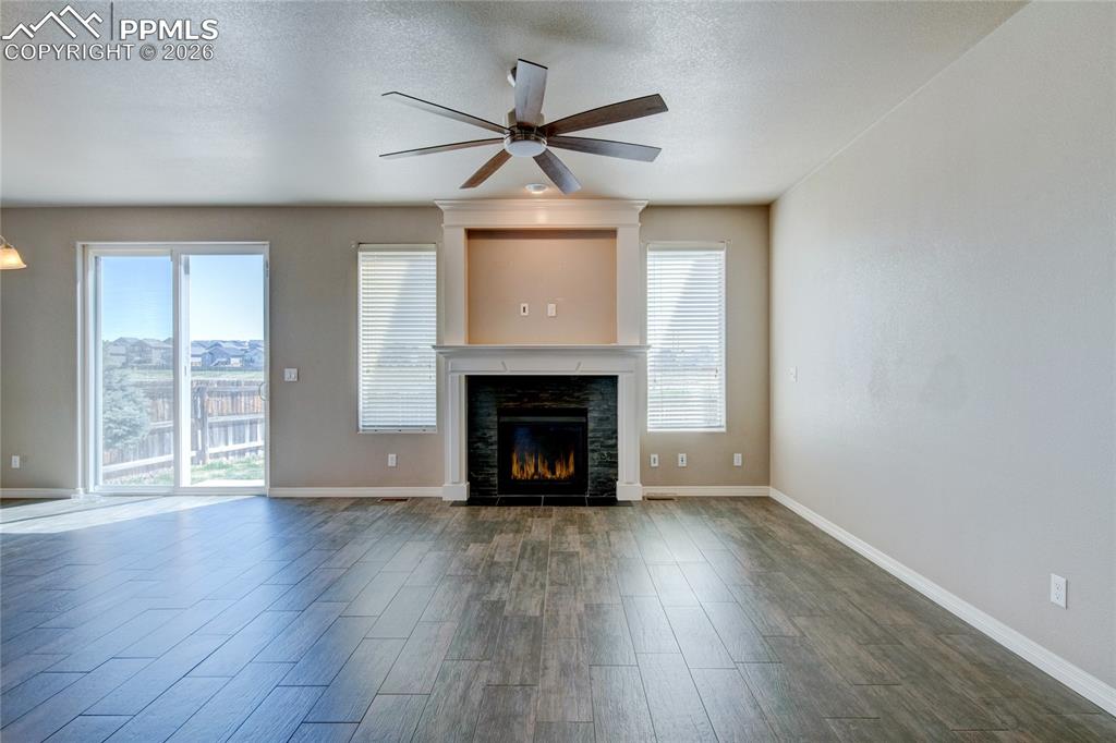 Image 6 of 36: The living area features wood-look tile flooring, a fireplace with a stone 