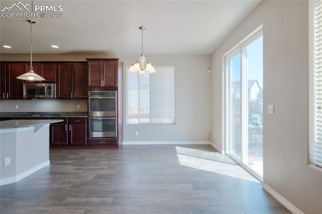 Image 9 of 36: This kitchen and dining area features rich wood cabinetry, granite countert
