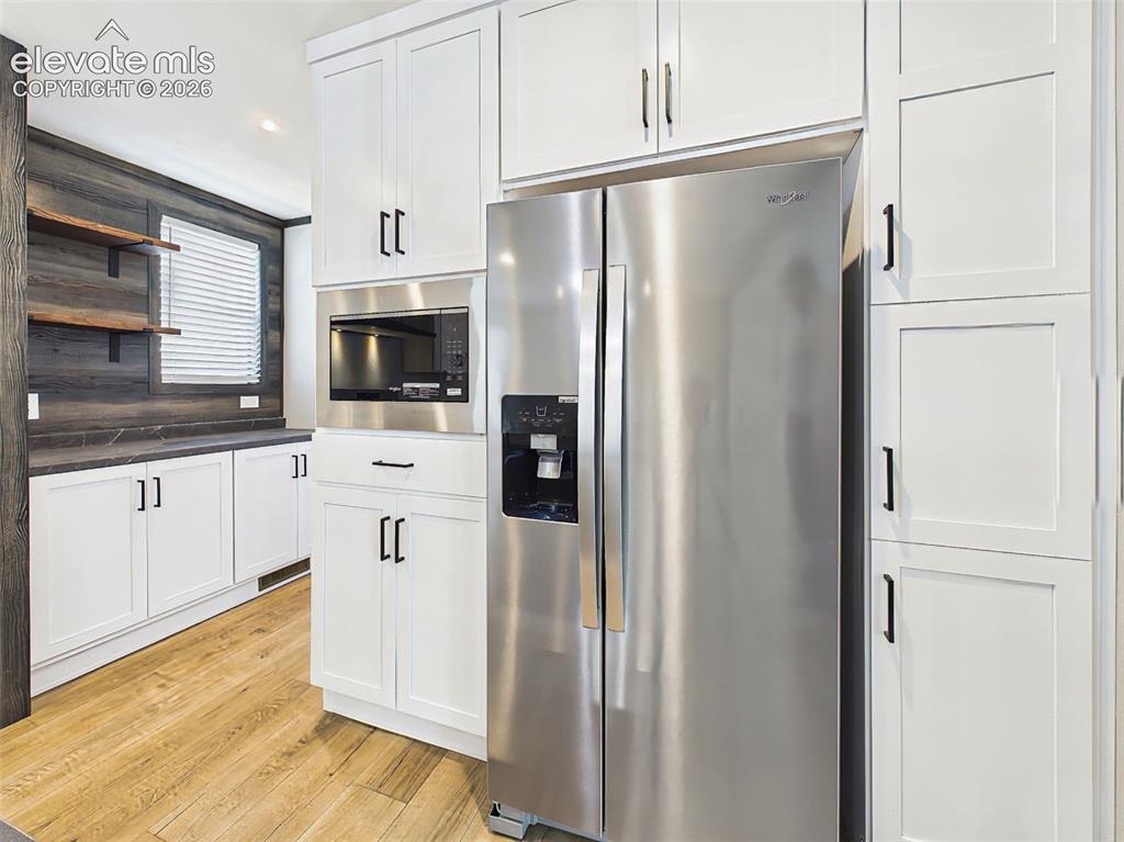 Image 19 of 50: Kitchen – Built-in microwave, stainless steel refrigerator, and floor-to-ce