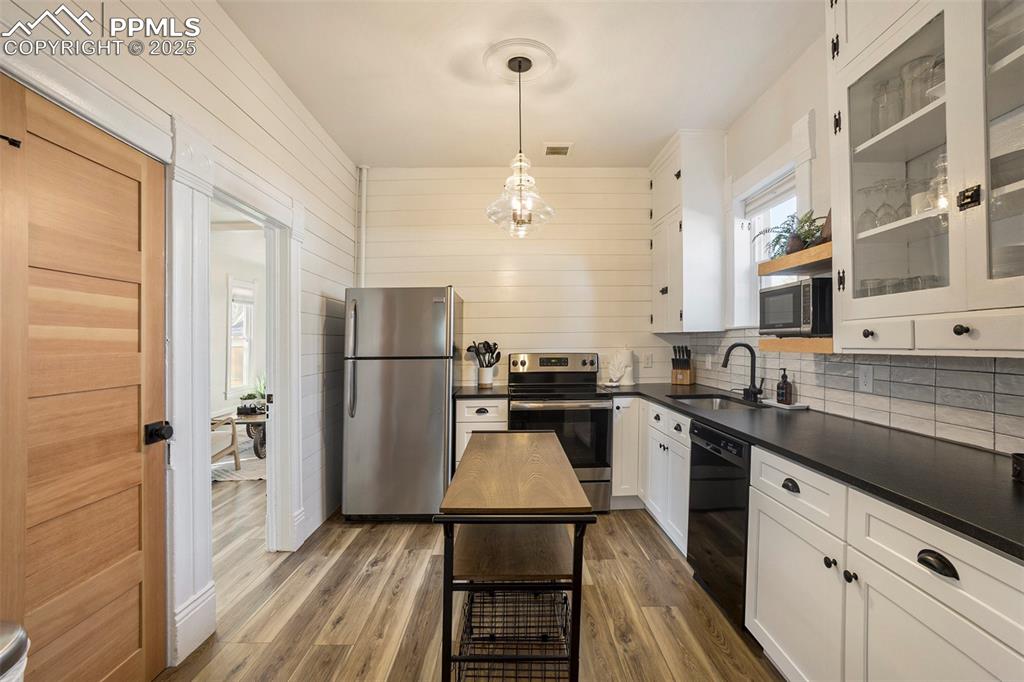 Image 11 of 38: Kitchen with white cabinets, stainless steel appliances, light wood-style f