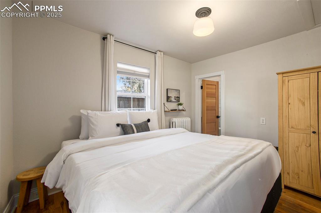 Image 12 of 38: Bedroom featuring wood finished floors and radiator