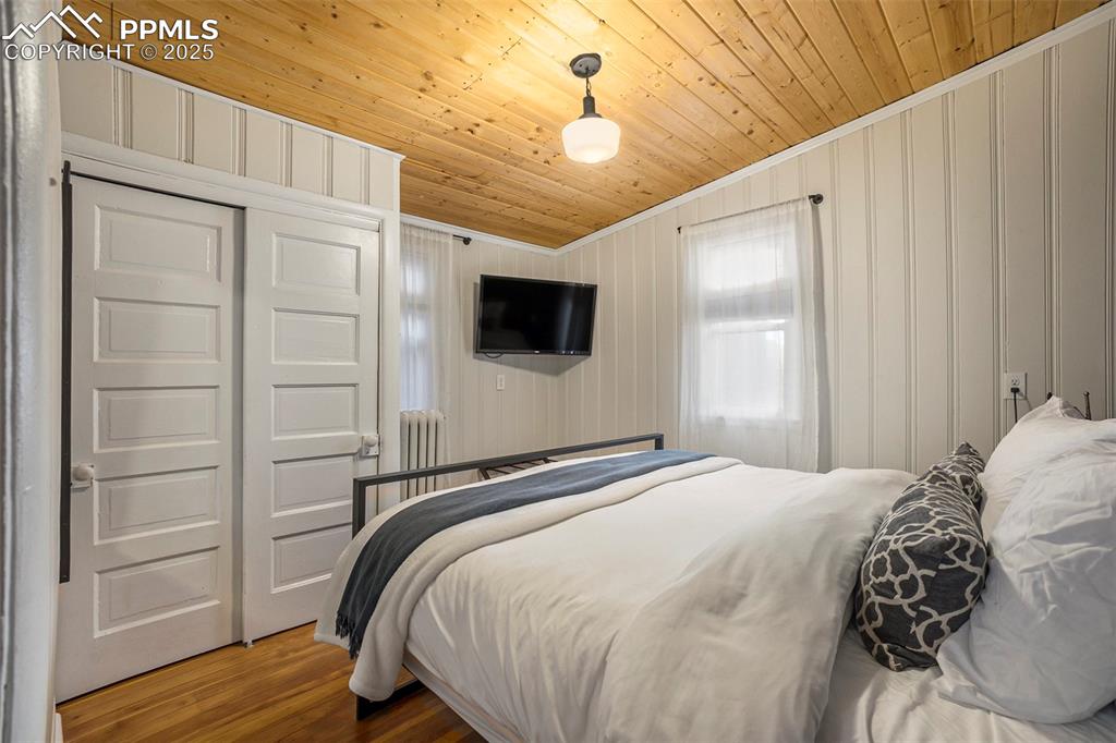 Image 15 of 38: Bedroom with wood finished floors, ornamental molding, a closet, and wood c