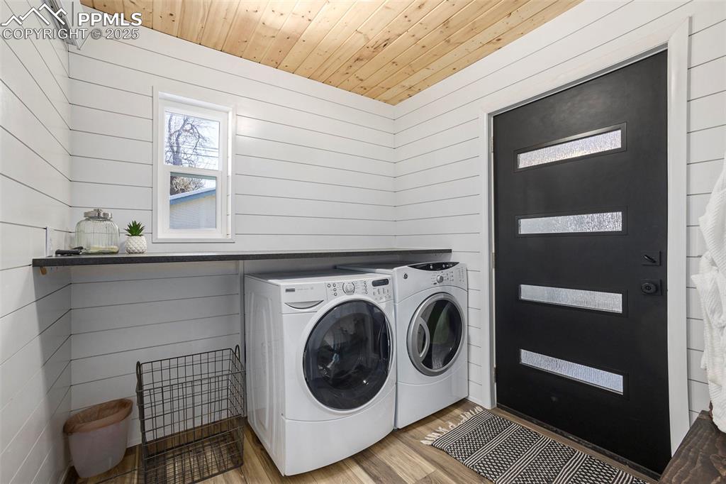 Image 17 of 38: Laundry area with wood finished floors, wood walls, independent washer and