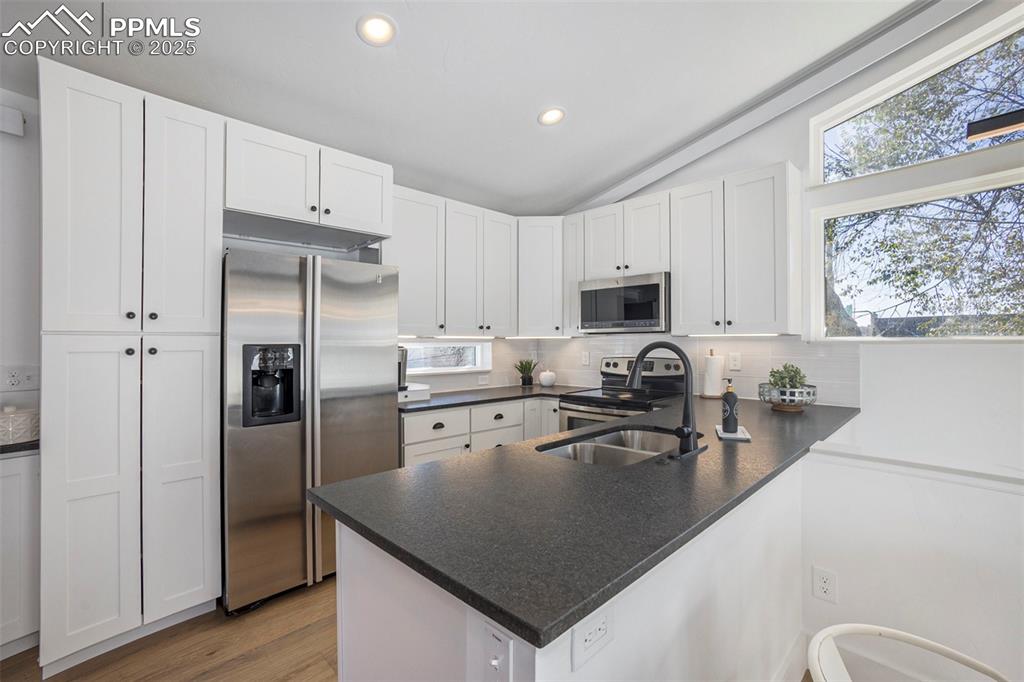 Image 24 of 38: Kitchen featuring stainless steel appliances, white cabinetry, decorative b