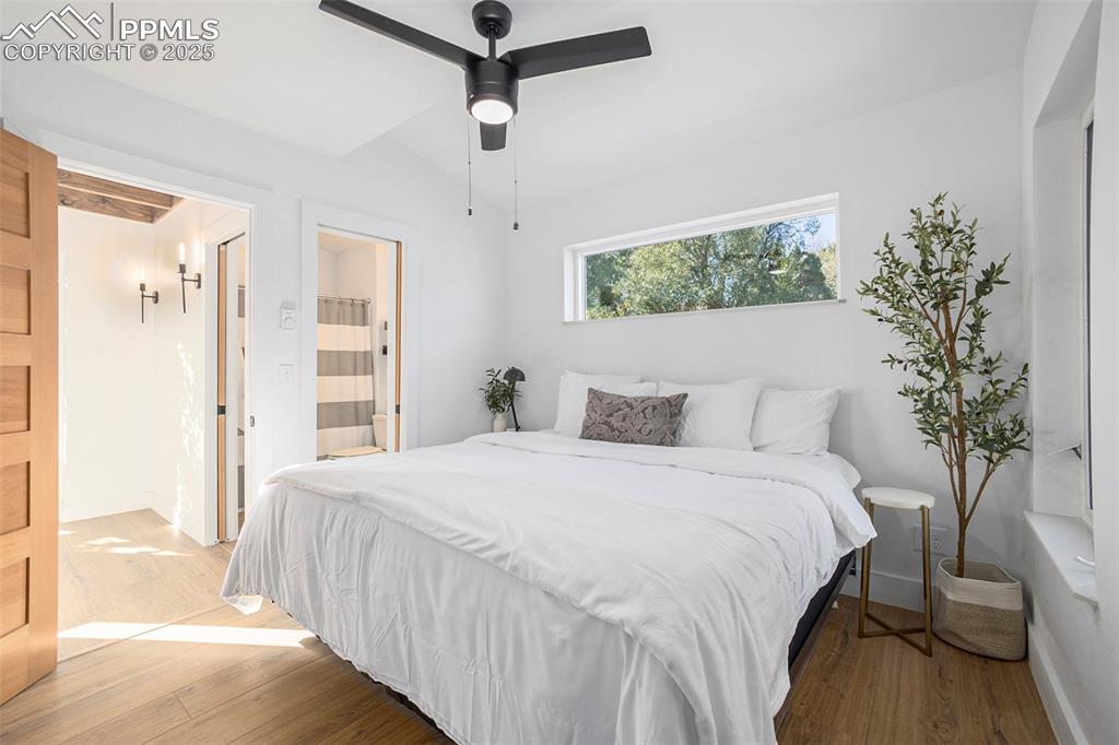Image 26 of 38: Bedroom with wood finished floors, connected bathroom, and a ceiling fan