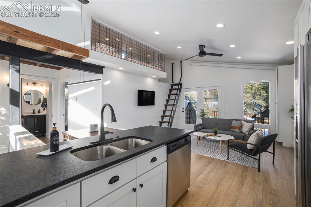 Image 28 of 38: Kitchen featuring white cabinetry, lofted ceiling, light wood finished floo