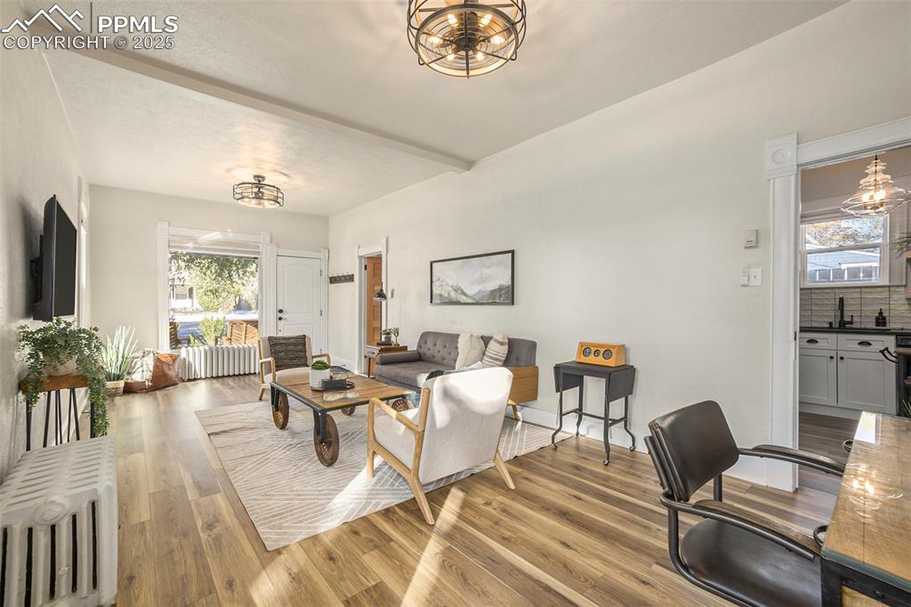Image 6 of 38: Living area with a chandelier, radiator, and light wood finished floors