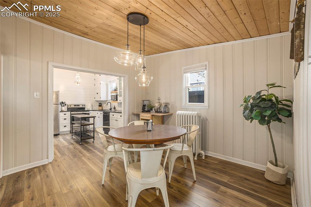 Image 7 of 38: Dining room with radiator heating unit, wood ceiling, light wood finished f
