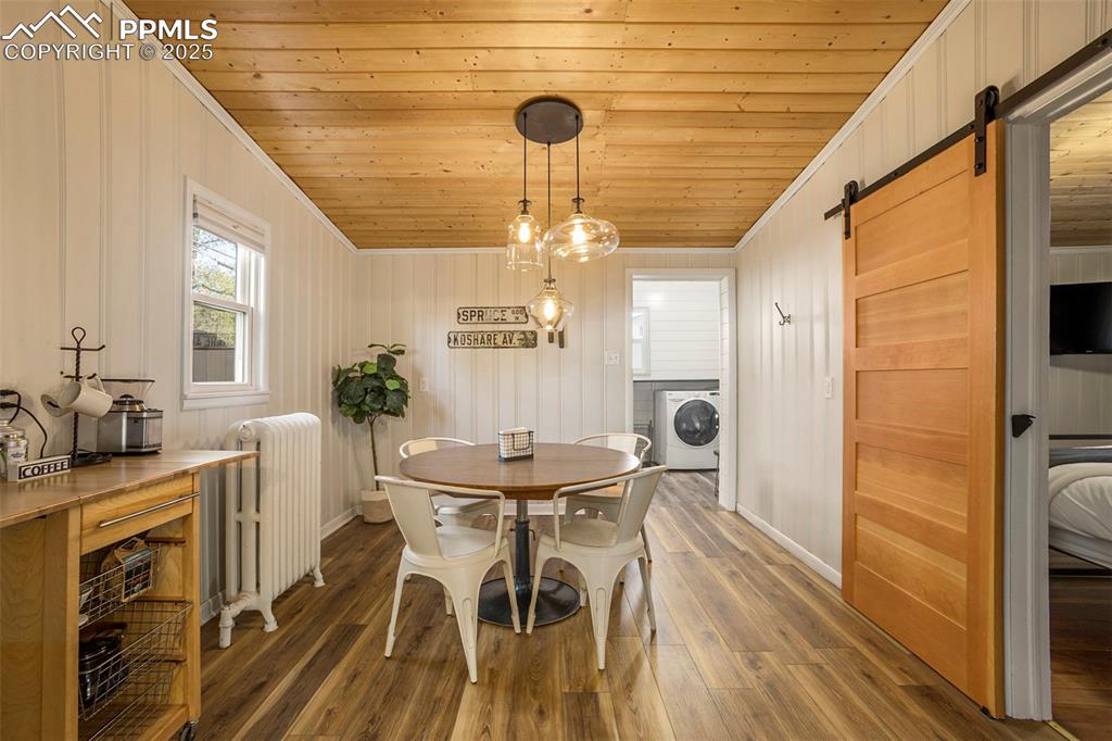 Image 8 of 38: Dining space with a barn door, radiator, wood ceiling, crown molding, and w