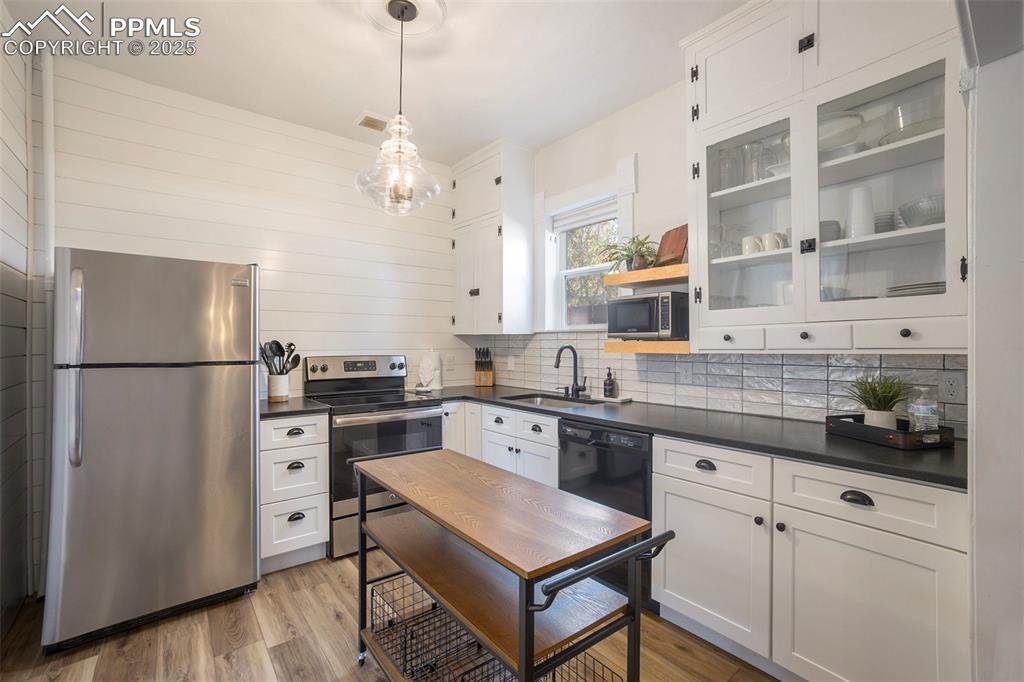 Image 9 of 38: Kitchen featuring white cabinetry, stainless steel appliances, pendant ligh