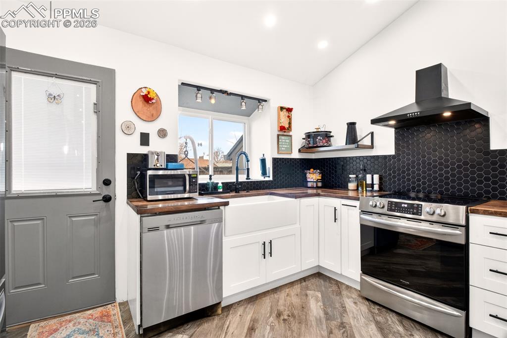 Image 8 of 17: Open shelving, hexagon-style backsplash and a wall mount hood. 