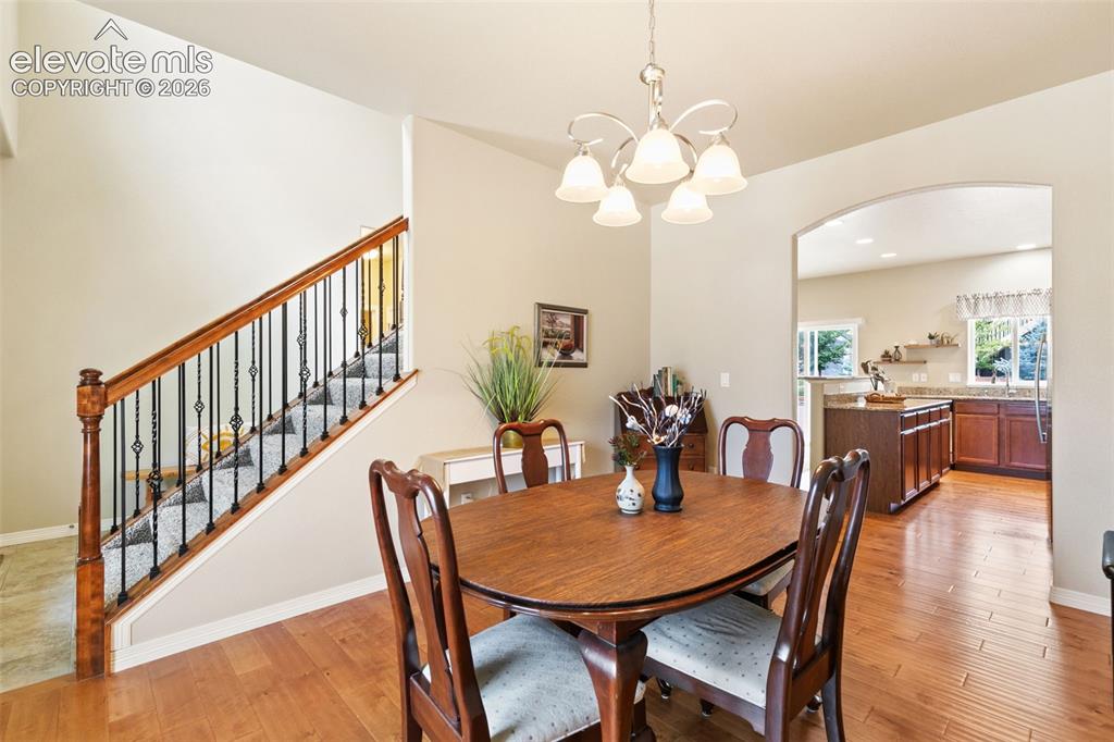 Image 13 of 27: Dining room with wood floors and chandelier, walk-through to the kitchen
