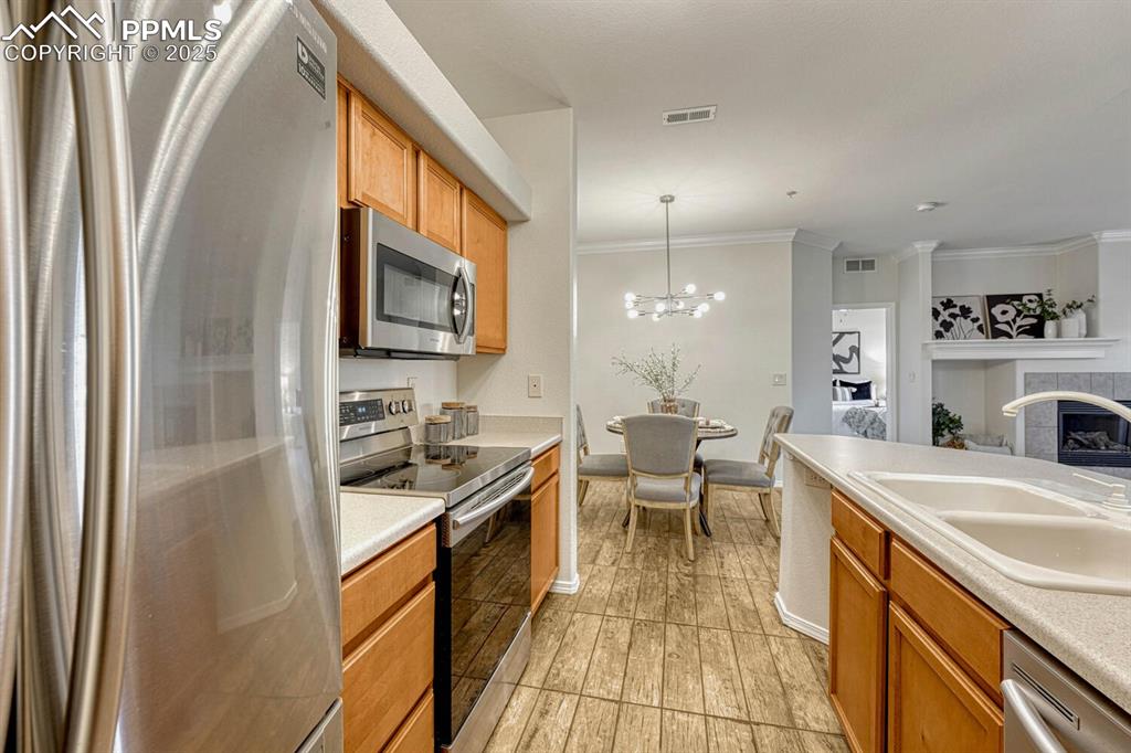 Image 5 of 27: Kitchen with stainless steel appliances, pendant lighting, light countertop