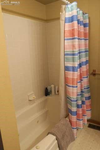 Image 15 of 36: Bathroom (in primary) featuring shower / bath combo with shower curtain