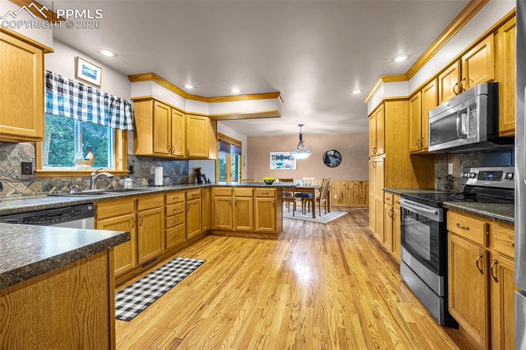 Image 6 of 36: Large kitchen featuring stainless steel appliances, a peninsula/bar for cas