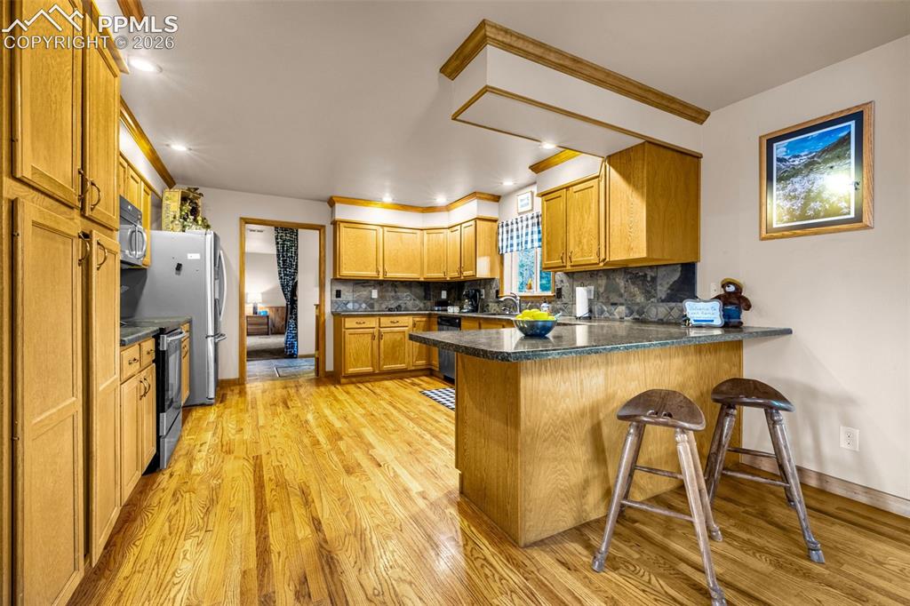 Image 7 of 36: Kitchen with appliances with stainless steel finishes, a peninsula, light w