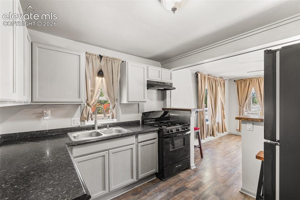 Image 11 of 23: Kitchen featuring light-toned cabinetry, dark speckled countertops, a black