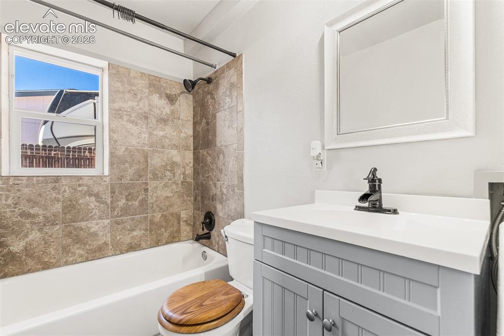 Image 14 of 23: Bathroom featuring a white bathtub, tiled shower surround, light-toned vani