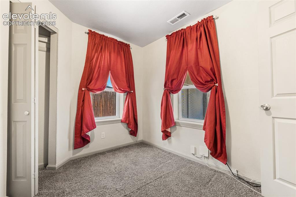 Image 16 of 23: Neutral-toned wall paint, two windows, wall-to-wall carpeting, and a closet