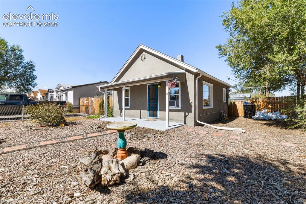 Image 2 of 23: Stucco exterior with a covered porch, multiple windows, and a sloped roof