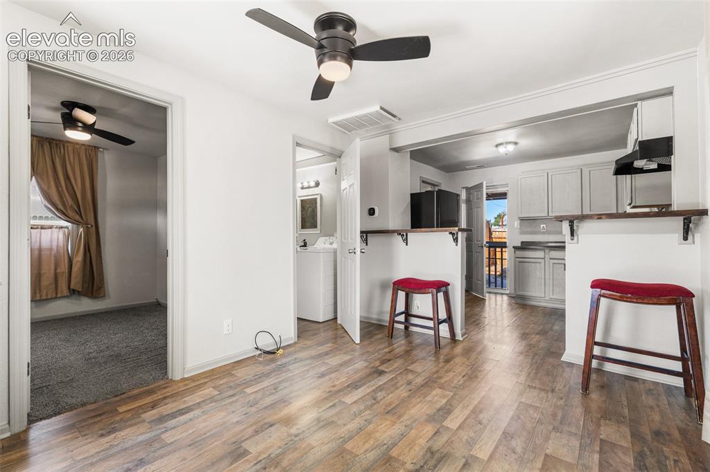 Image 4 of 23: Wood-finish flooring throughout, with a recessed kitchen featuring light-co