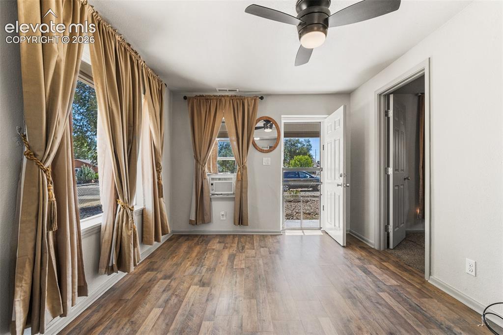Image 6 of 23: Wood-finish flooring, two large windows, overhead ceiling fan with lighting